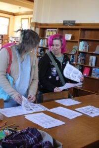 Two young participants picking up their materials